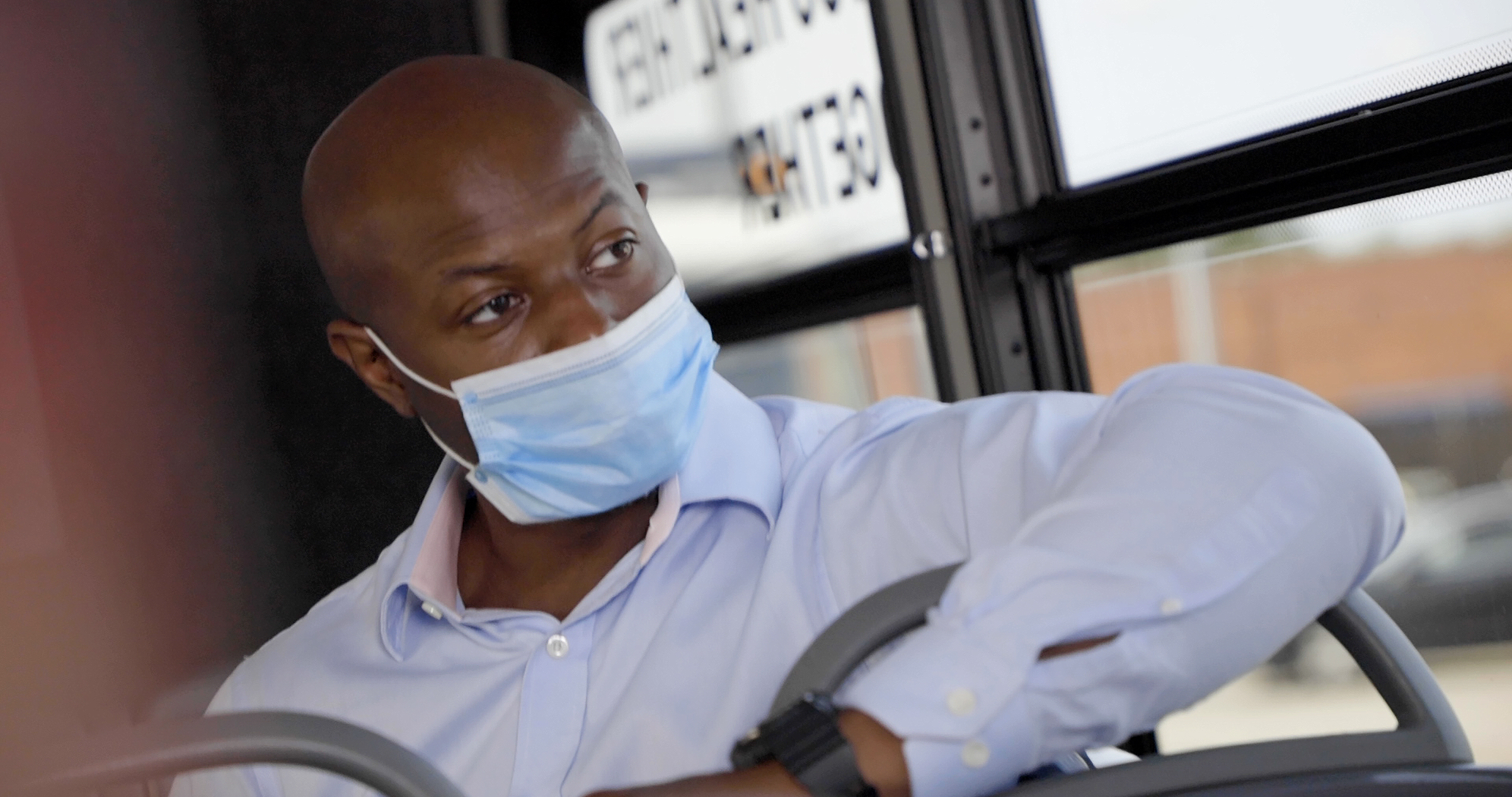 Masked man in suit riding bus