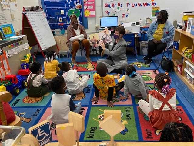 CEO Julie Timm reads a book to a class seated on the floor