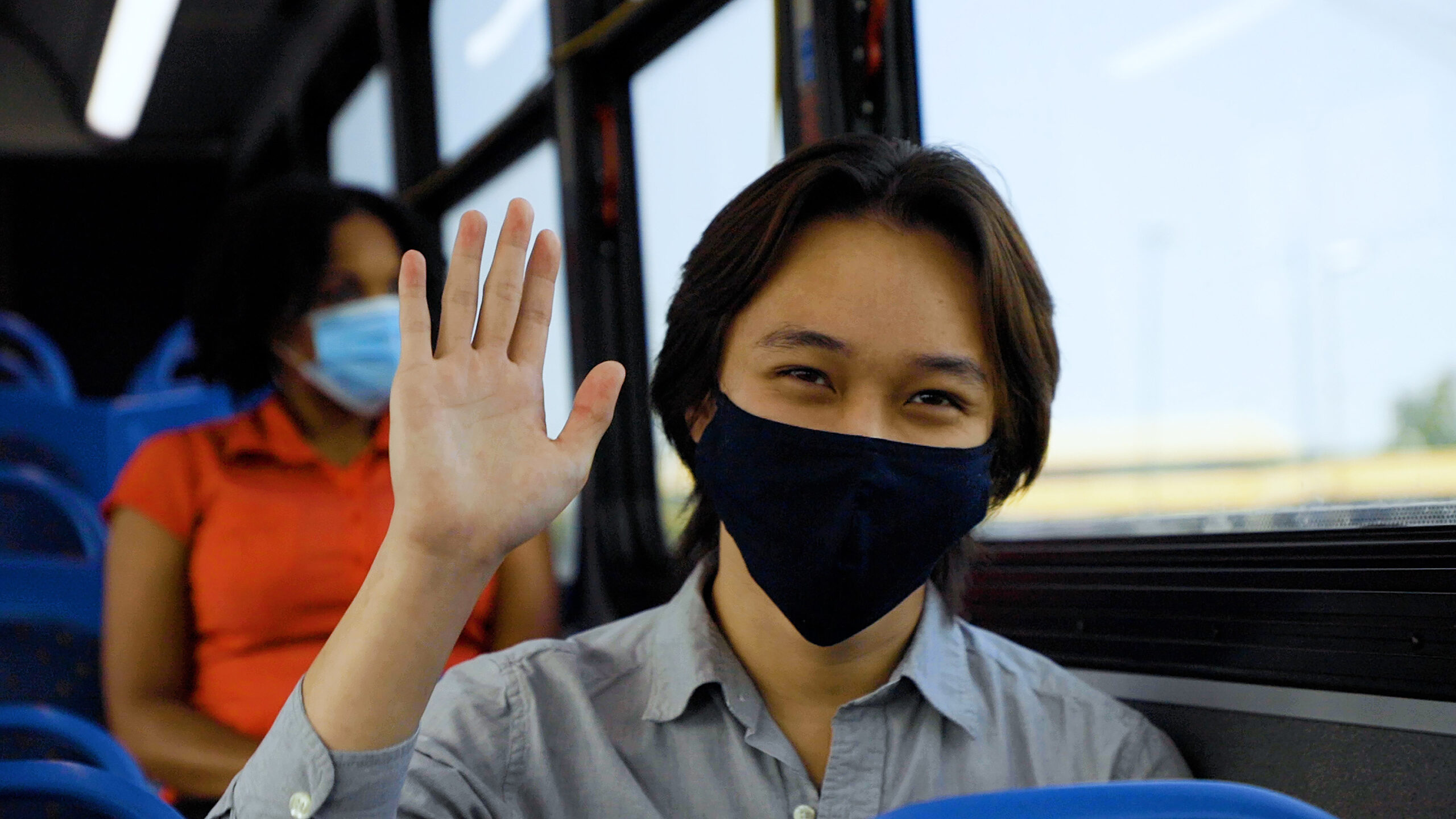 A passenger wearing a face mask waves