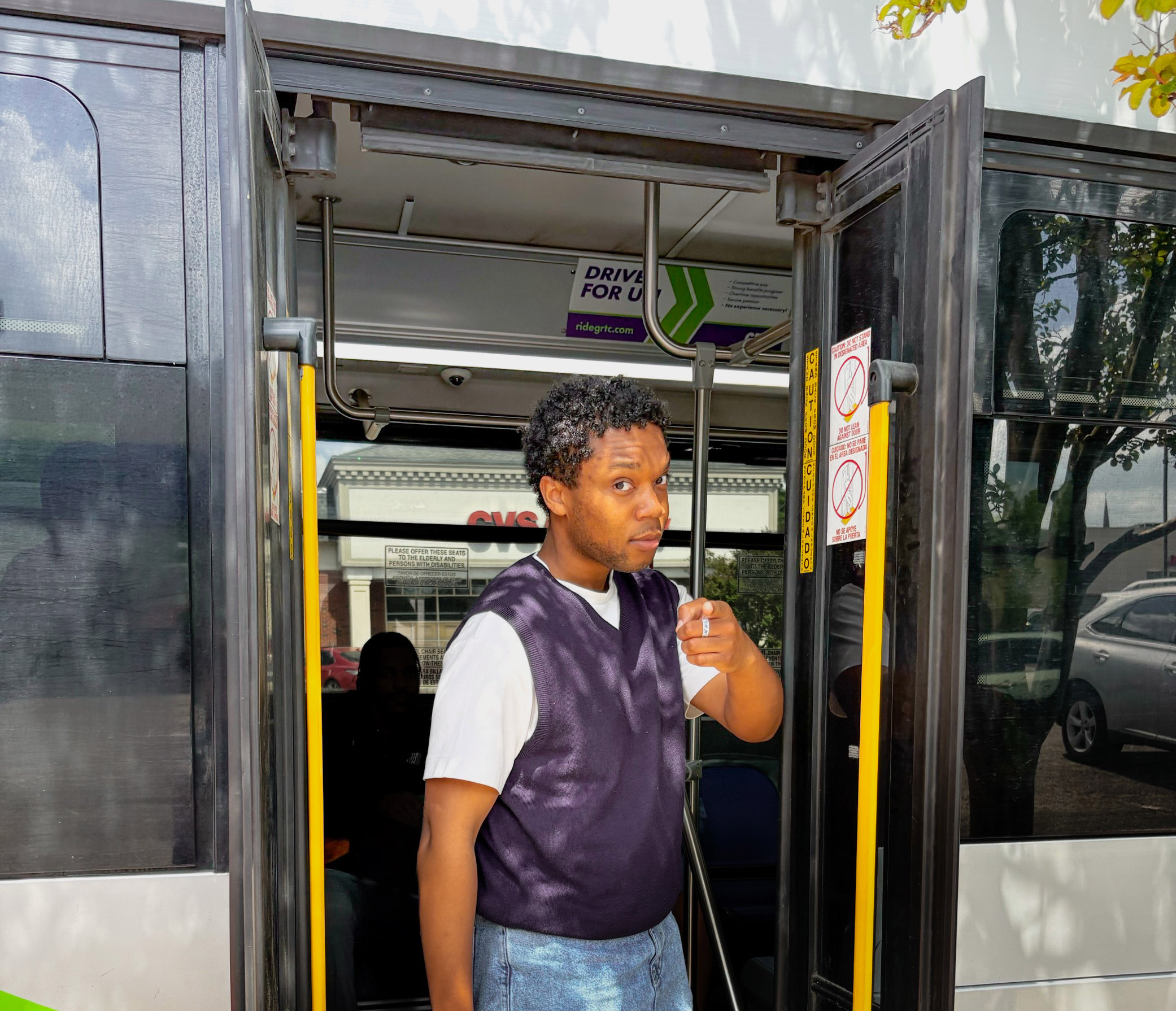 young rider standing in the open door of a bus pointing at the viewer, in reference to the Uncle Sam recruitment post